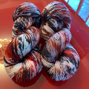 Hand Dyed Fingering Weight Superwash Merino cashmere nylon yarn in speckled red and black on white yarn