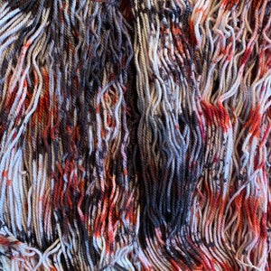 Hand Dyed Fingering Weight Superwash Merino cashmere nylon yarn in speckled red and black on white yarn