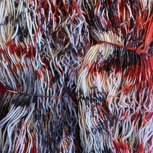 Hand Dyed Fingering Weight Superwash Merino cashmere nylon yarn in speckled red and black on white yarn